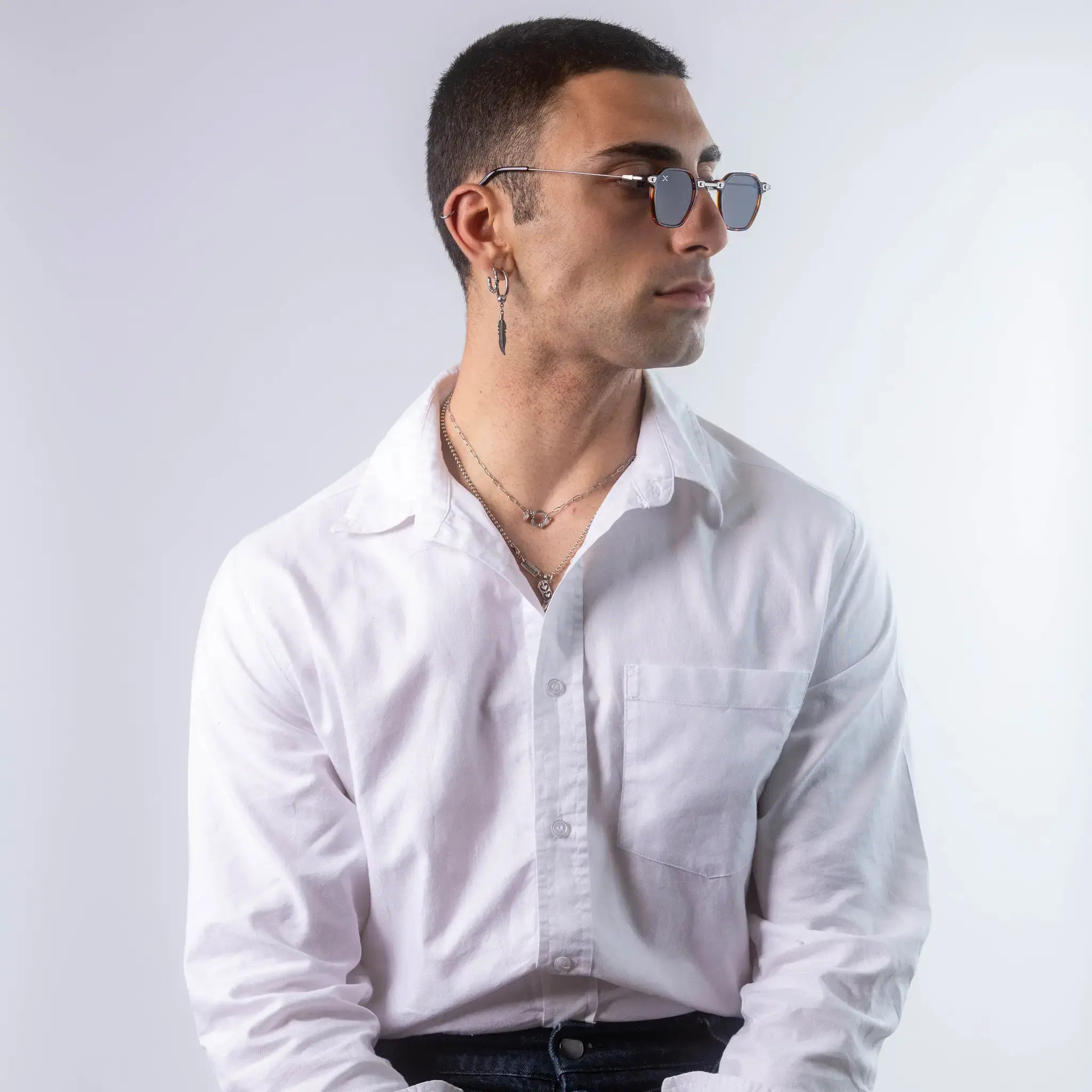 A male model wearing Exposure Sunglasses polarized sunglasses with silver frames and tinted lenses, posing against a white background.