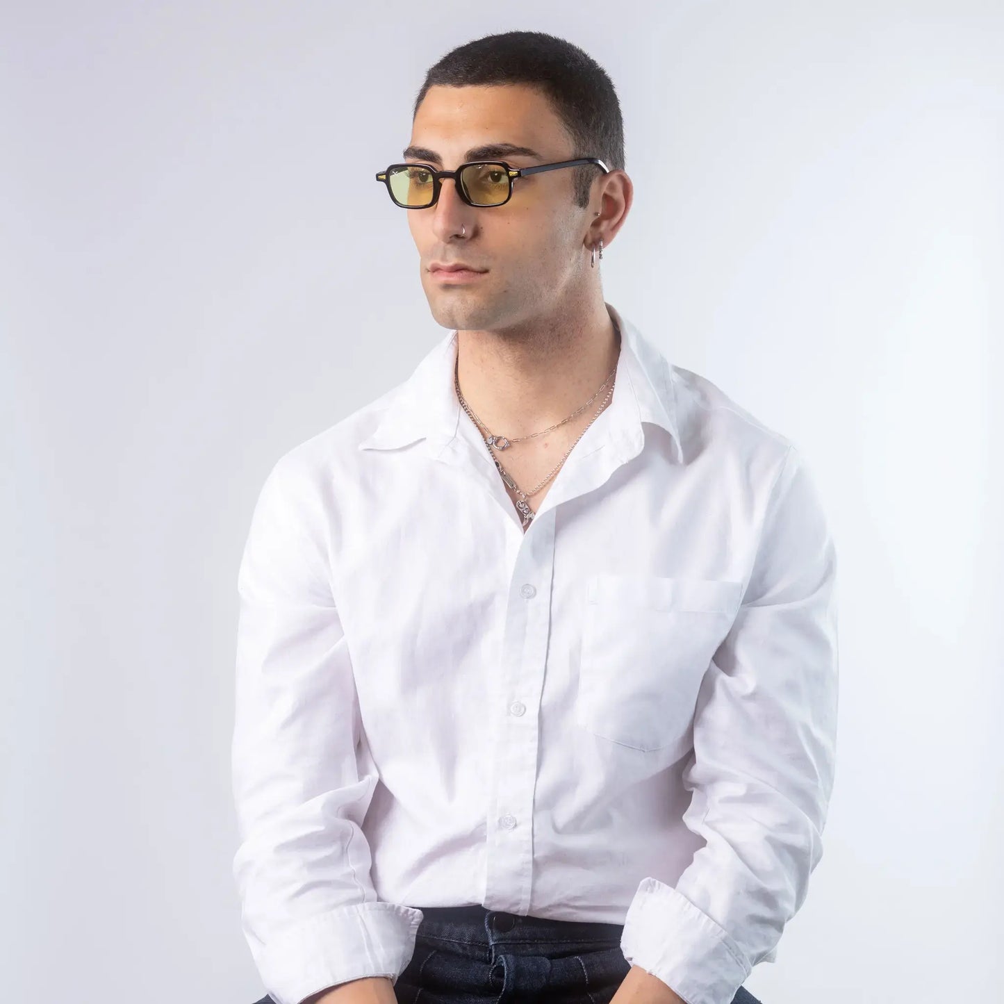 A male model wearing Exposure Sunglasses polarized sunglasses with black frames and green lenses, posing against a white background.