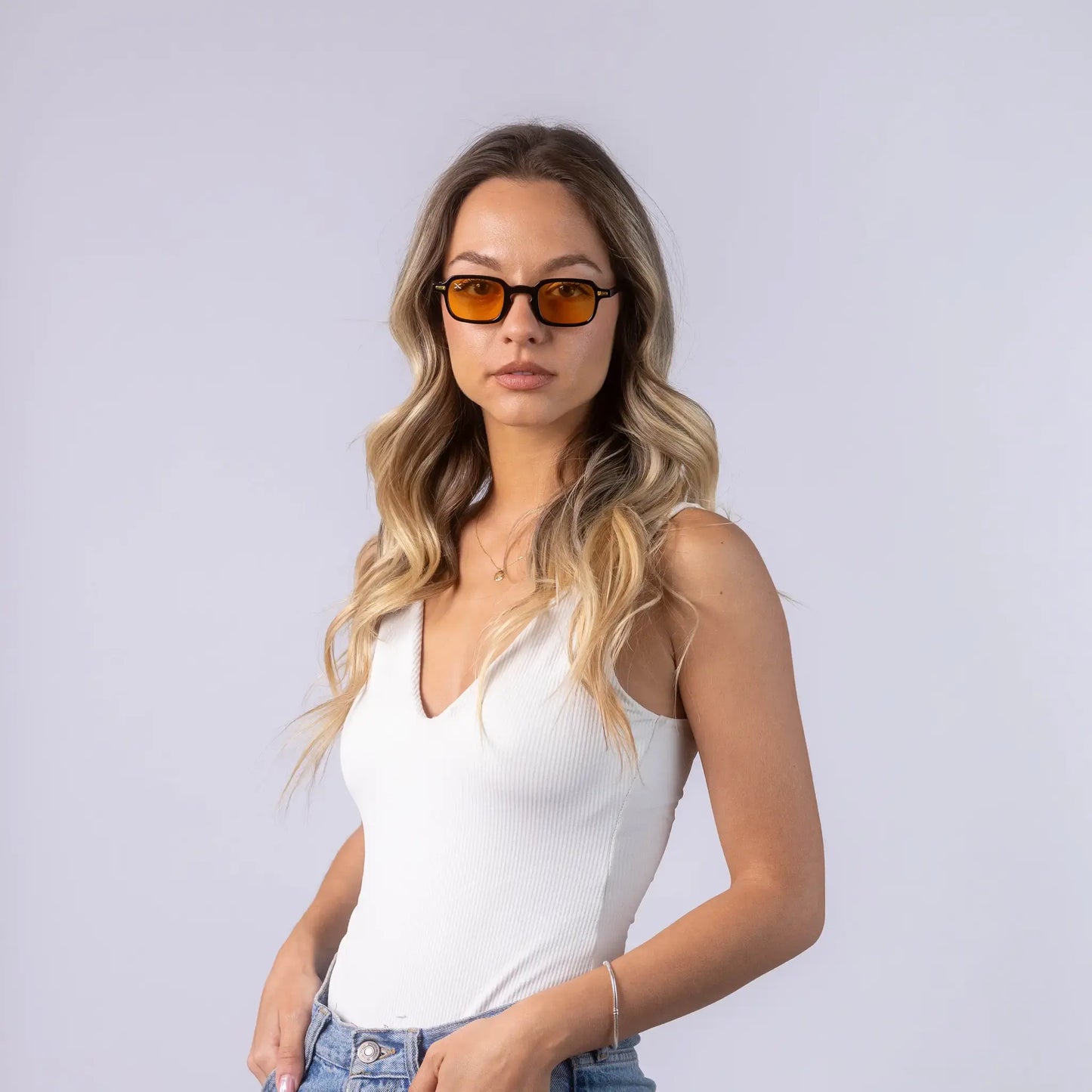 A female model wearing Exposure Sunglasses polarized sunglasses with black frames and orange lenses, posing against a white background.
