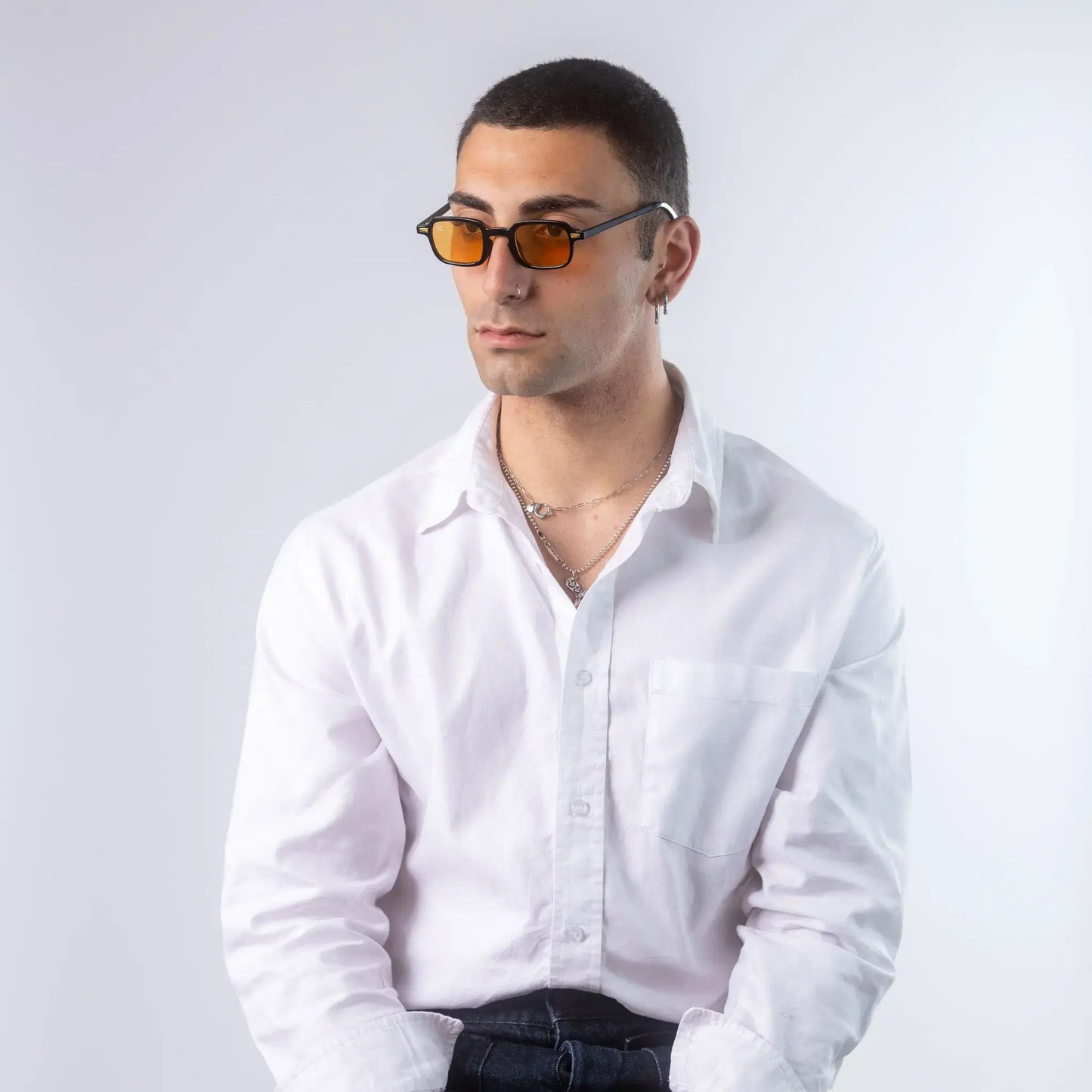 A male model wearing Exposure Sunglasses polarized sunglasses with black frames and orange lenses, posing against a white background.