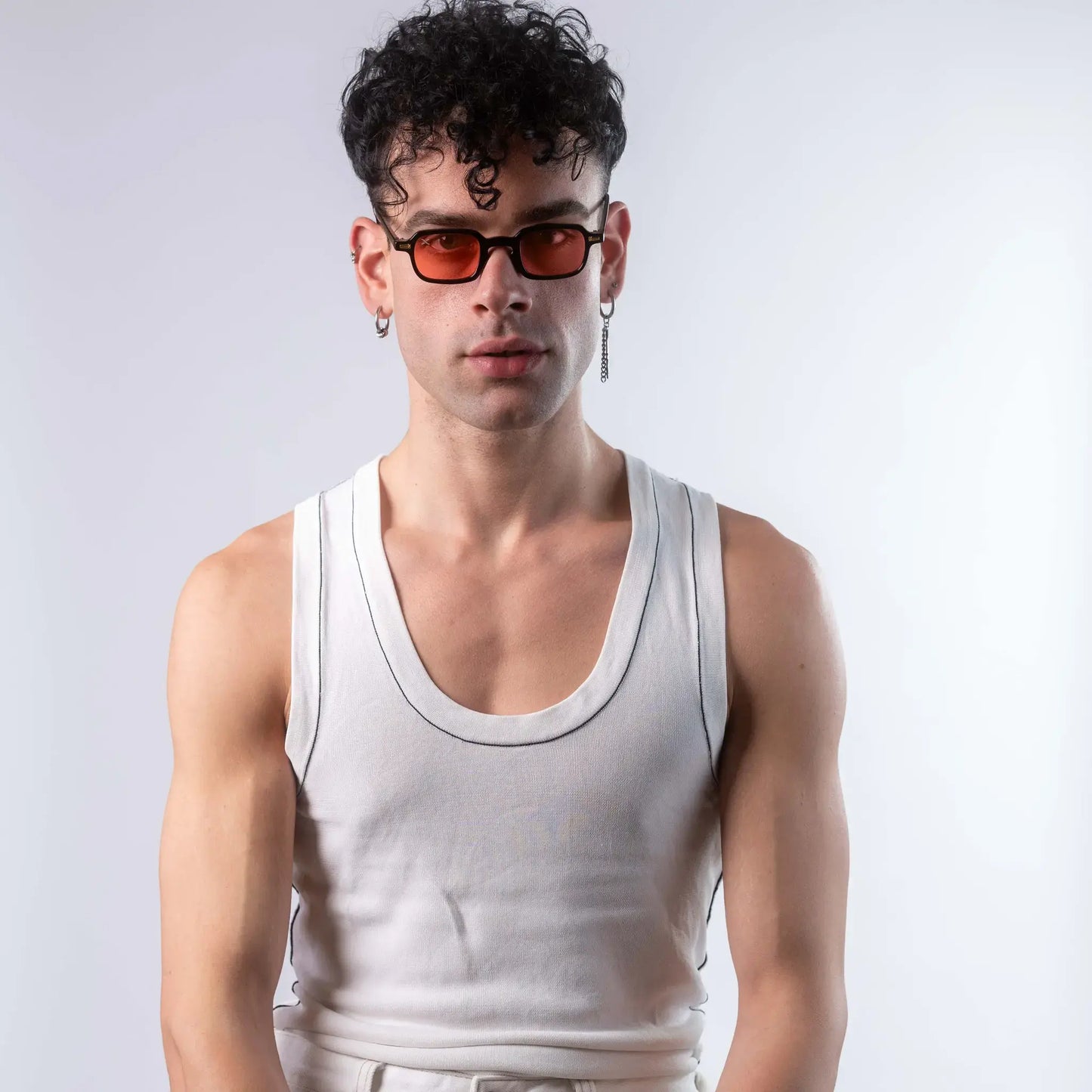 A male model wearing Exposure Sunglasses polarized sunglasses with black frames and red lenses, posing against a white background.