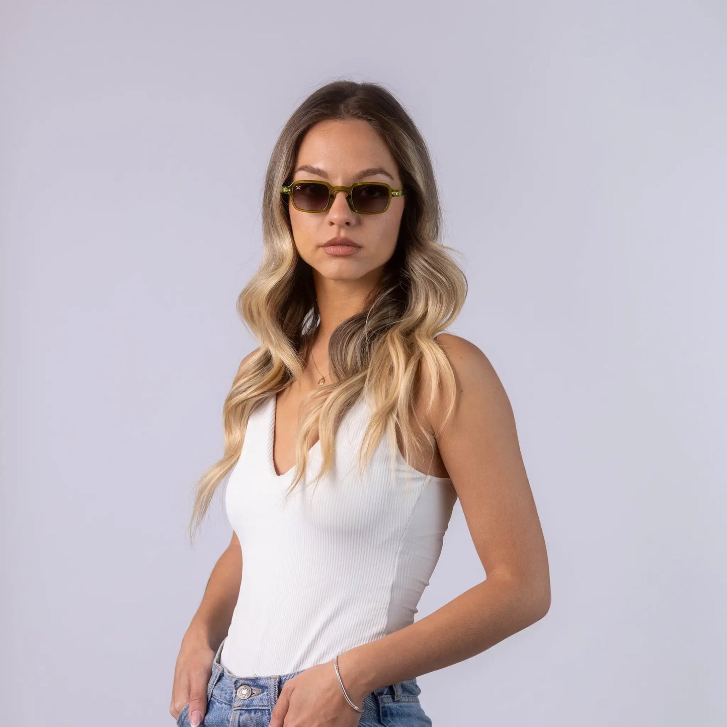 A female model wearing Exposure Sunglasses polarized sunglasses with green frames and green lenses, posing against a white background.