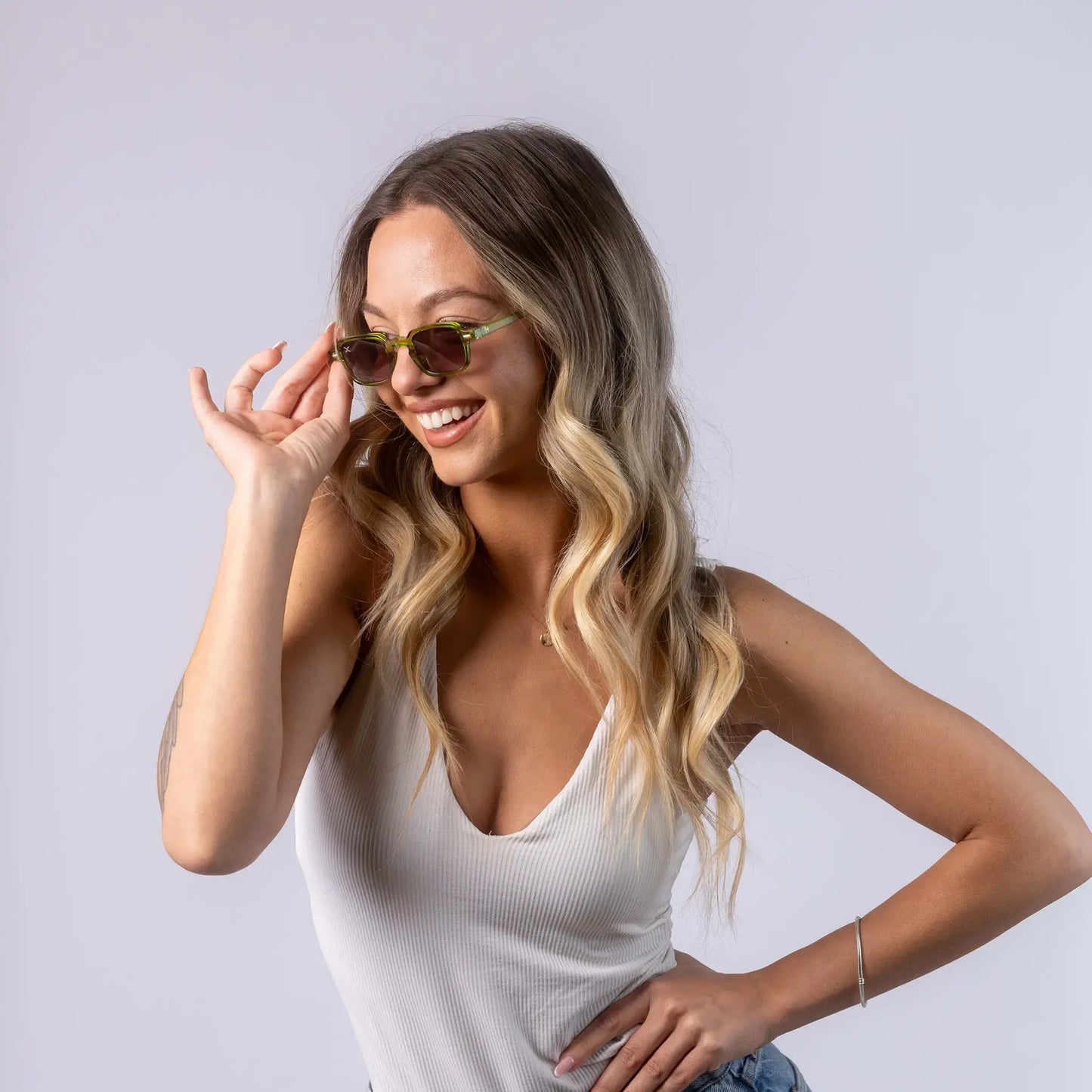 A female model wearing Exposure Sunglasses polarized sunglasses with green frames and green lenses, posing against a white background.