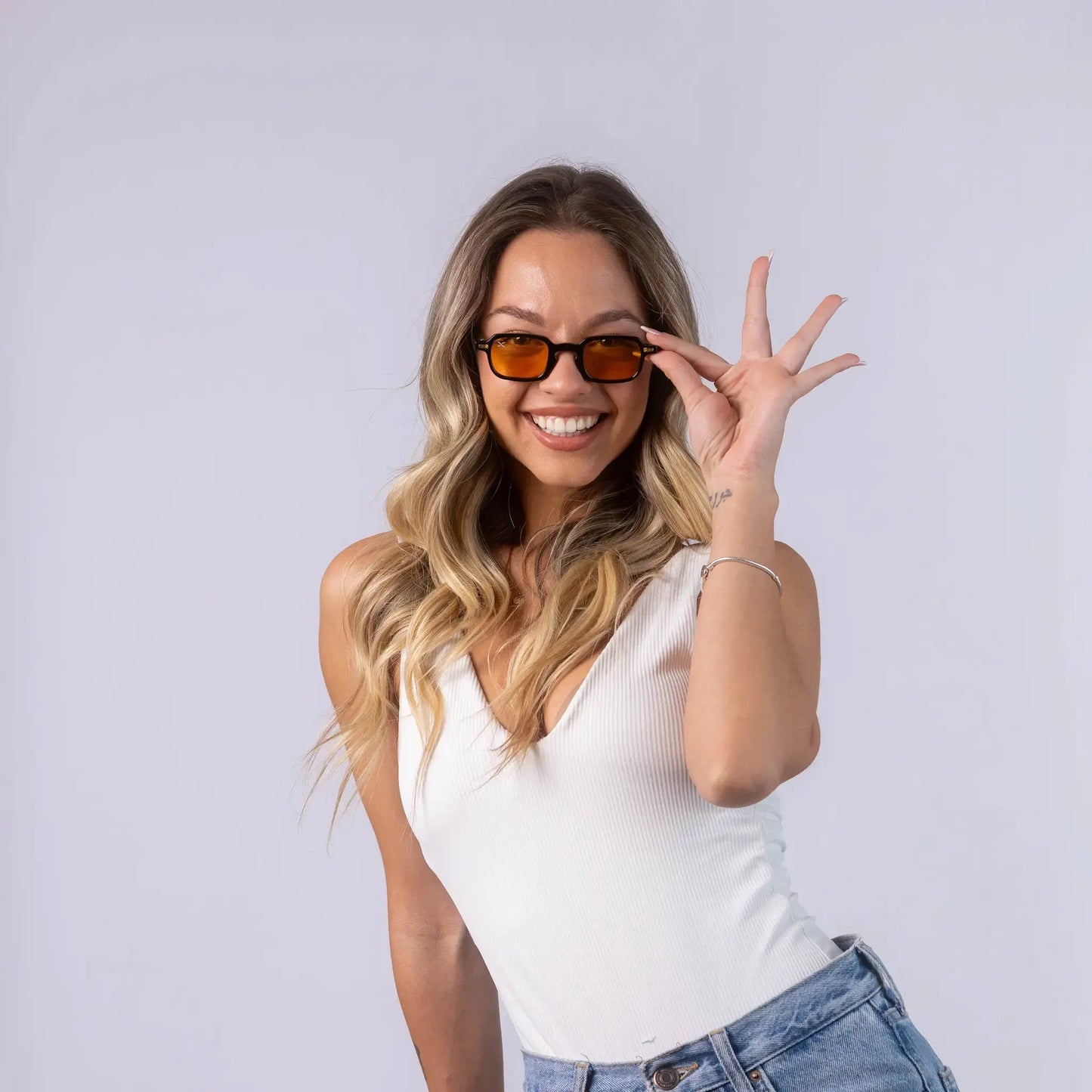 A female model wearing Exposure Sunglasses polarized sunglasses with black frames and orange lenses, posing against a white background.